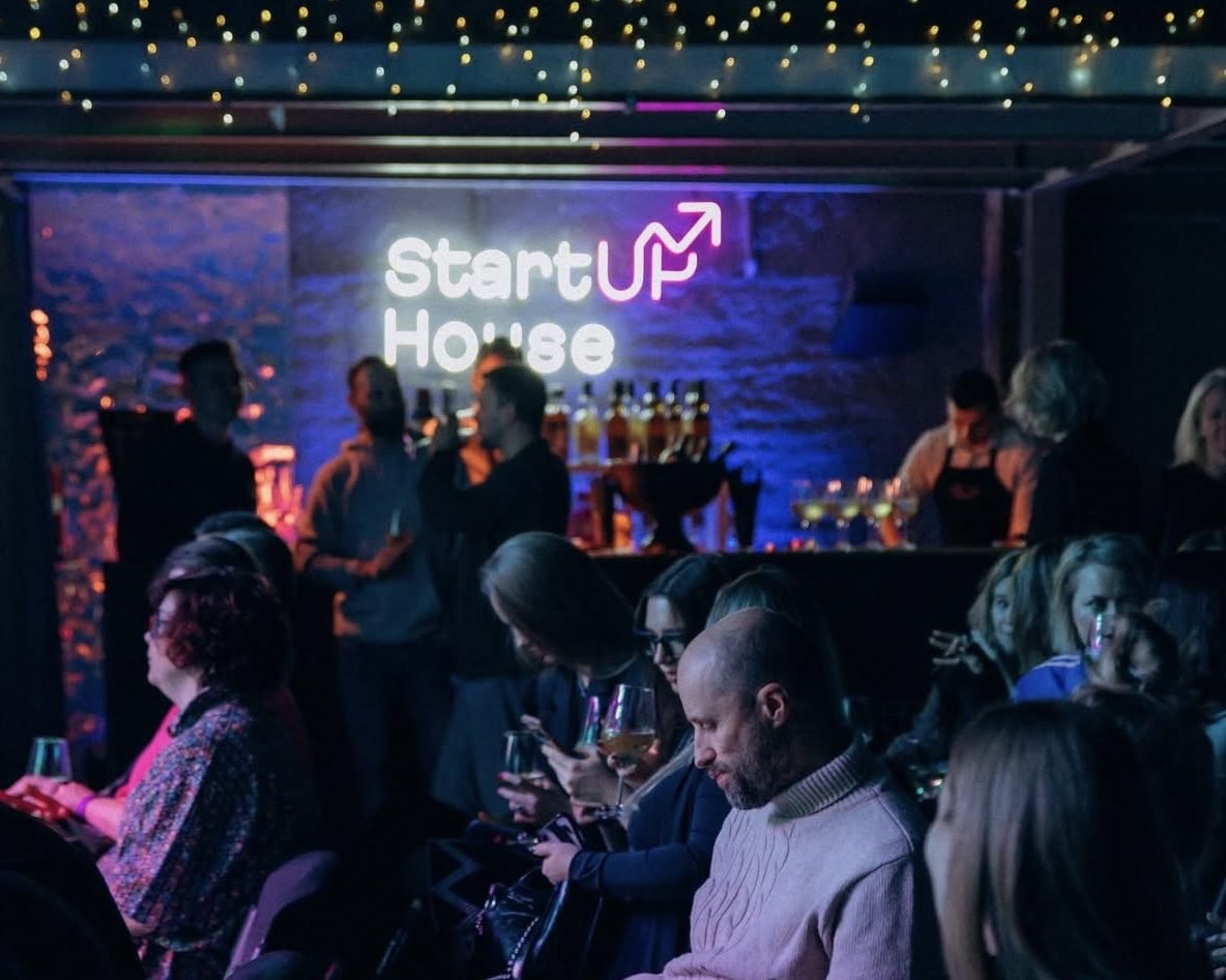 Logotyp i kallvit neon ovanför baren under ett event